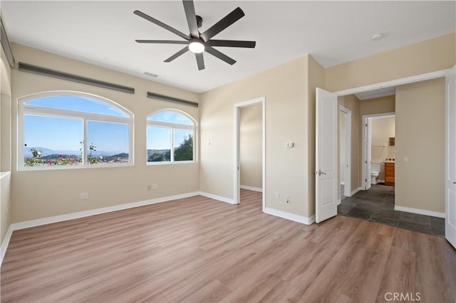 unfurnished bedroom with light wood-type flooring, ceiling fan, and ensuite bathroom