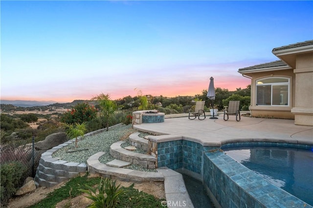 pool at dusk featuring a patio area and a jacuzzi