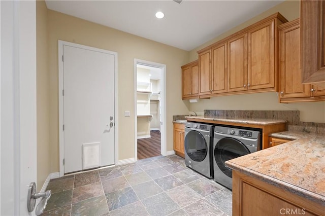 clothes washing area featuring cabinets and washer and clothes dryer