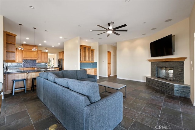 living room featuring ceiling fan, sink, and a fireplace