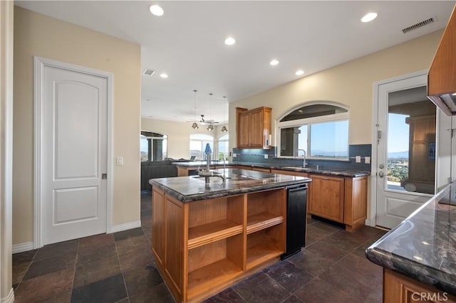 kitchen with kitchen peninsula, decorative light fixtures, sink, tasteful backsplash, and a center island