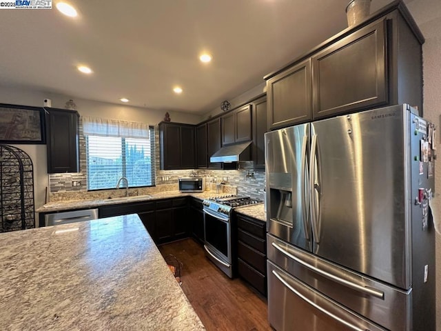 kitchen with light stone countertops, sink, decorative backsplash, and appliances with stainless steel finishes