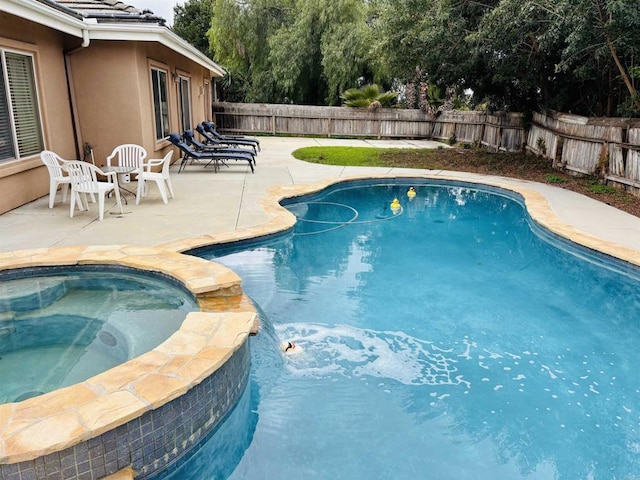 view of swimming pool featuring a patio area, a fenced backyard, and a pool with connected hot tub