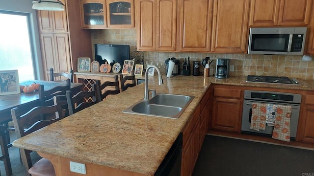 kitchen with stainless steel appliances, a sink, a peninsula, and decorative backsplash