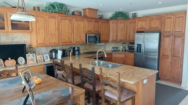 kitchen featuring a breakfast bar area, stainless steel appliances, a peninsula, a sink, and tasteful backsplash