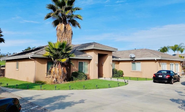 view of front of house featuring concrete driveway, a front lawn, and stucco siding