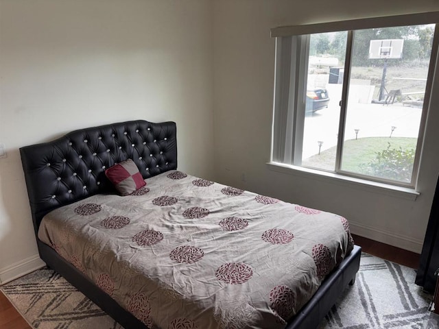 bedroom featuring multiple windows, wood finished floors, and baseboards