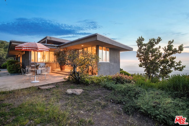 property exterior at dusk with a patio area