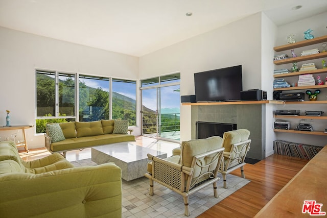 living room with a tile fireplace and light hardwood / wood-style flooring