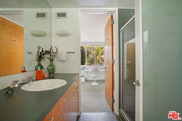 bathroom featuring a shower with door and vanity