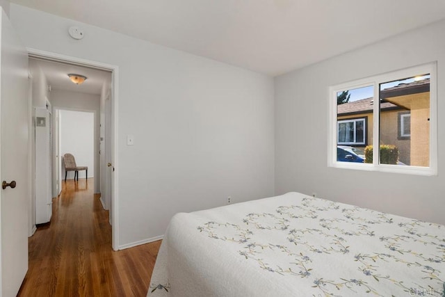 bedroom with dark wood-type flooring and fridge