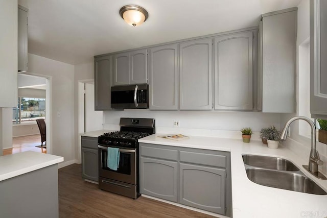 kitchen featuring sink, dark hardwood / wood-style flooring, gray cabinetry, and stainless steel appliances