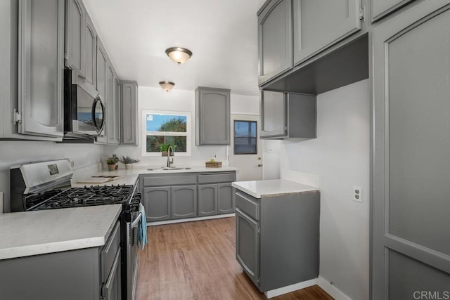 kitchen featuring hardwood / wood-style flooring, sink, gray cabinets, and stainless steel appliances