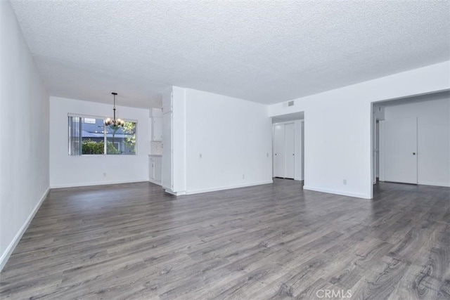 unfurnished living room with a textured ceiling, dark wood-type flooring, and a notable chandelier