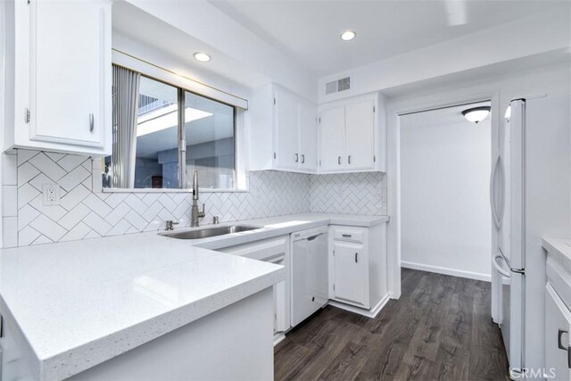 kitchen with white appliances, tasteful backsplash, white cabinetry, sink, and dark wood-type flooring