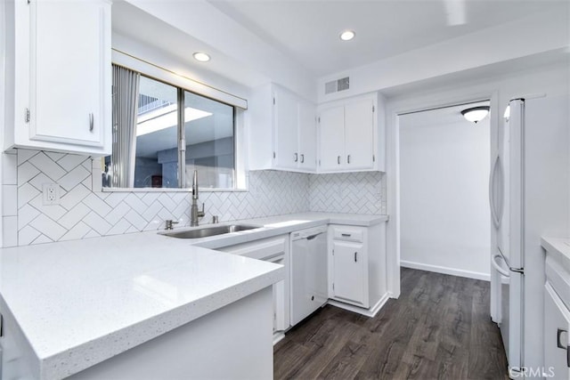 kitchen featuring white appliances, visible vents, decorative backsplash, white cabinets, and a sink