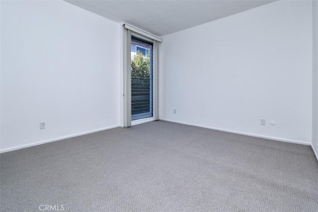 spare room with baseboards and dark colored carpet