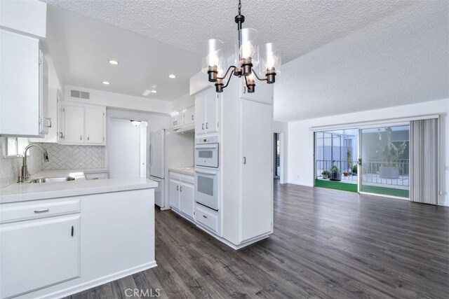 kitchen with pendant lighting, sink, white cabinets, tasteful backsplash, and a textured ceiling