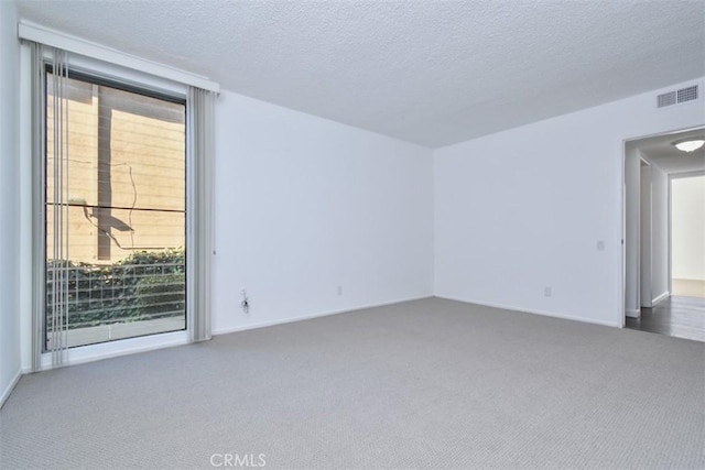 carpeted empty room with a textured ceiling