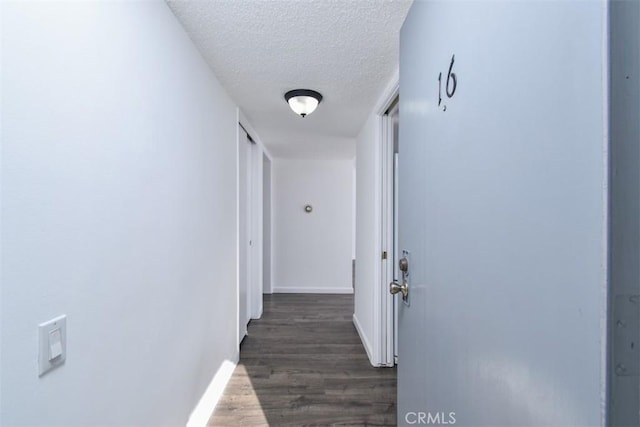 hallway featuring dark wood-style flooring, a textured ceiling, and baseboards