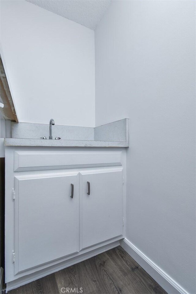 clothes washing area featuring sink, a textured ceiling, and dark hardwood / wood-style flooring