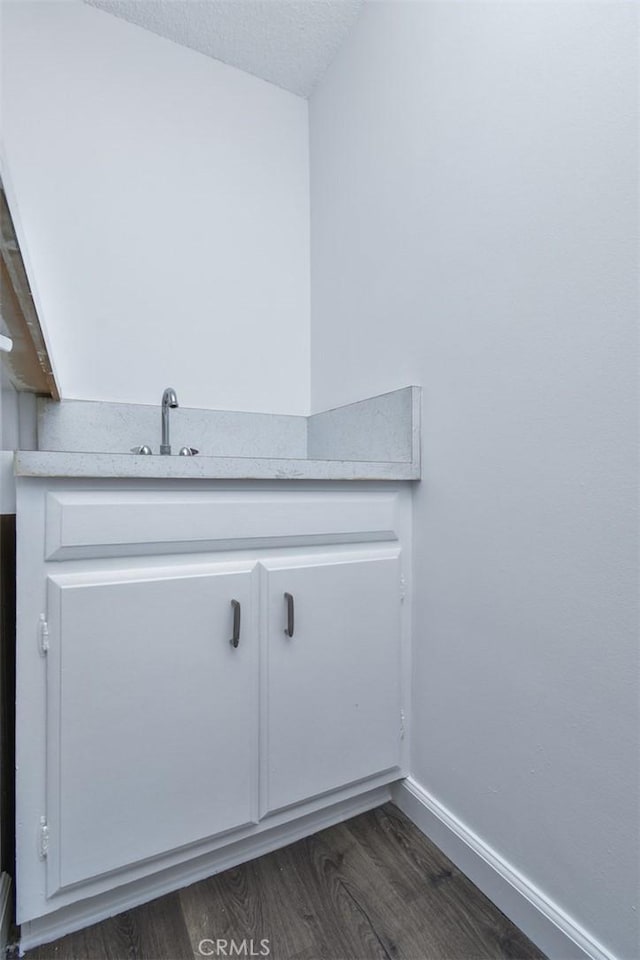 interior space featuring a sink, a textured ceiling, baseboards, and wood finished floors