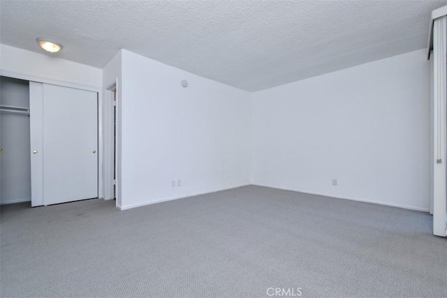 unfurnished bedroom featuring carpet flooring, a textured ceiling, and a closet