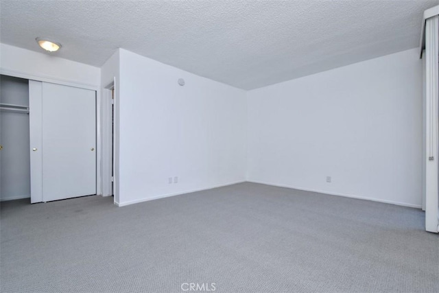 unfurnished bedroom featuring carpet, a textured ceiling, and a closet