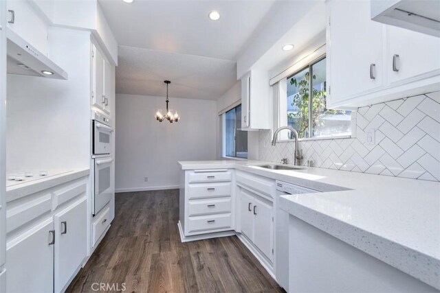 kitchen with sink, white cabinetry, kitchen peninsula, and hanging light fixtures