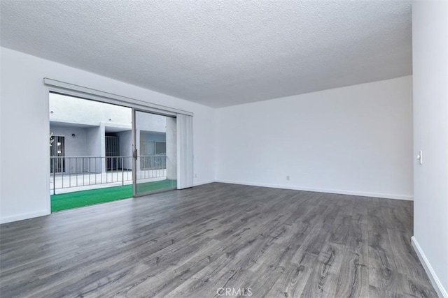 spare room featuring a textured ceiling, wood finished floors, and baseboards