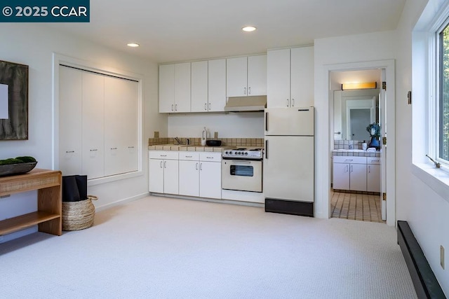 kitchen featuring white cabinets, white appliances, and light carpet