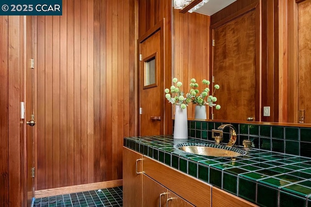 bathroom with tile patterned floors, vanity, and wooden walls