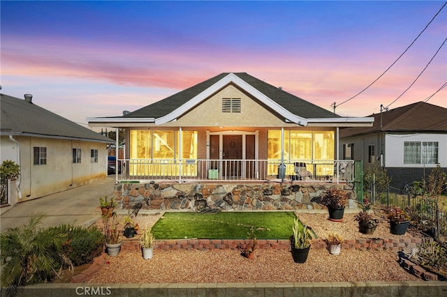 back house at dusk featuring a porch