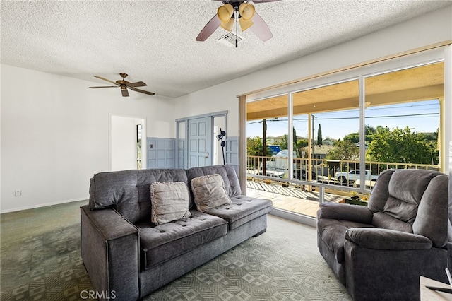 living room with ceiling fan, carpet floors, and a textured ceiling