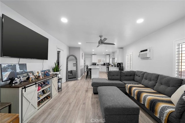 living room with light wood-type flooring, a wall mounted air conditioner, a healthy amount of sunlight, and ceiling fan