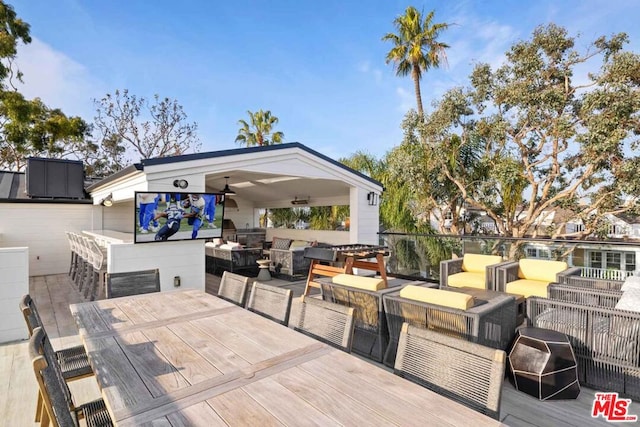 wooden deck with ceiling fan and outdoor lounge area