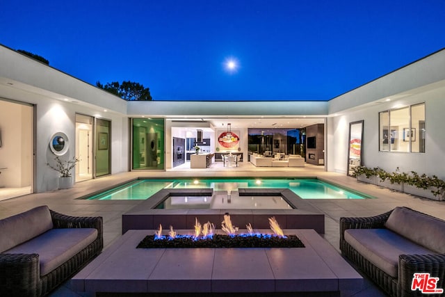 pool at twilight featuring a patio area and an outdoor living space with a fire pit