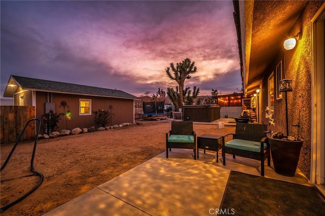 patio terrace at dusk with a hot tub and a trampoline