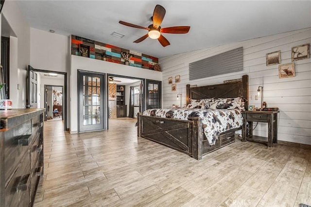 bedroom with ceiling fan, vaulted ceiling, and wooden walls