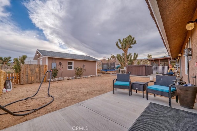 view of patio / terrace with a hot tub, an outdoor structure, and a trampoline