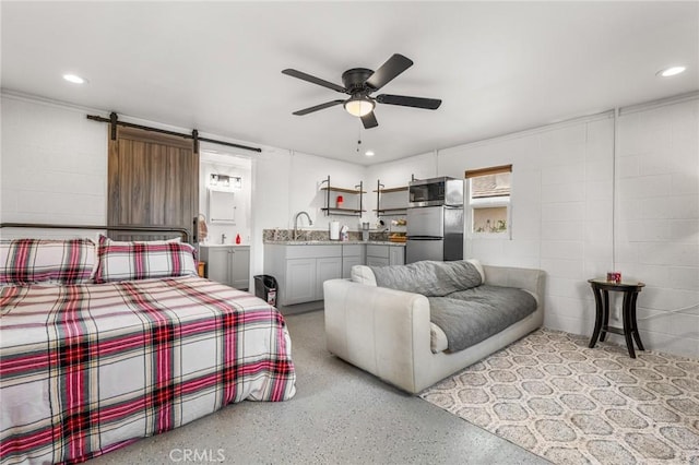 bedroom with sink, stainless steel refrigerator, ceiling fan, and a barn door