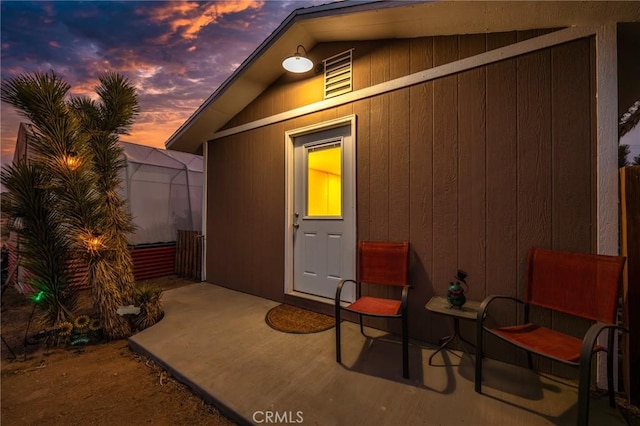 patio terrace at dusk featuring an outbuilding