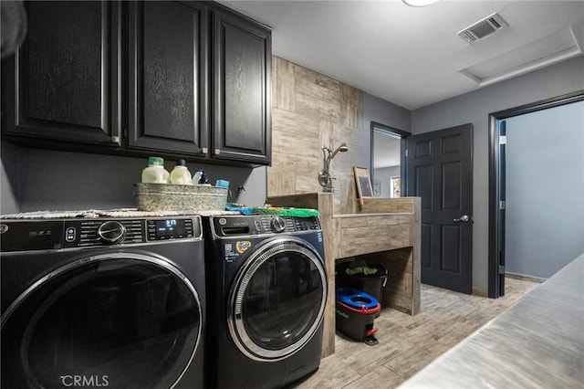 laundry area with cabinets, light hardwood / wood-style flooring, and washing machine and clothes dryer