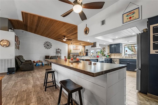 kitchen with kitchen peninsula, light wood-type flooring, wood ceiling, a kitchen bar, and lofted ceiling