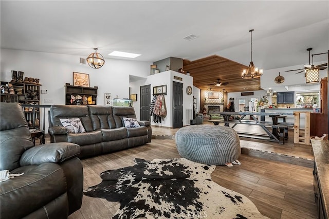 living room with light wood-type flooring, vaulted ceiling, and ceiling fan with notable chandelier