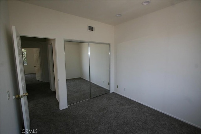 unfurnished bedroom featuring a closet and dark colored carpet