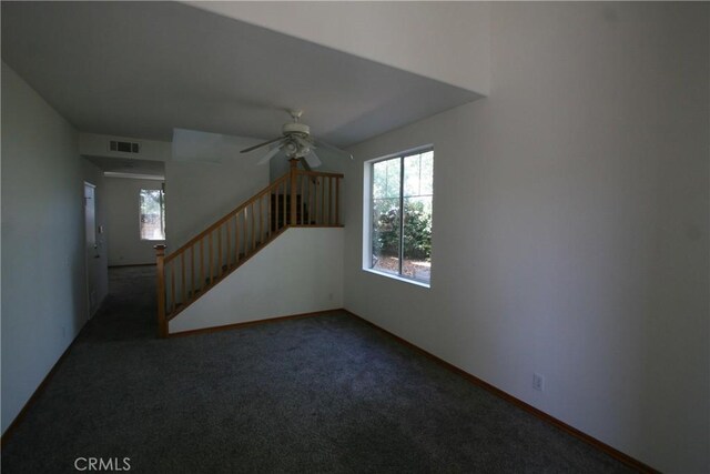 spare room with ceiling fan and dark carpet