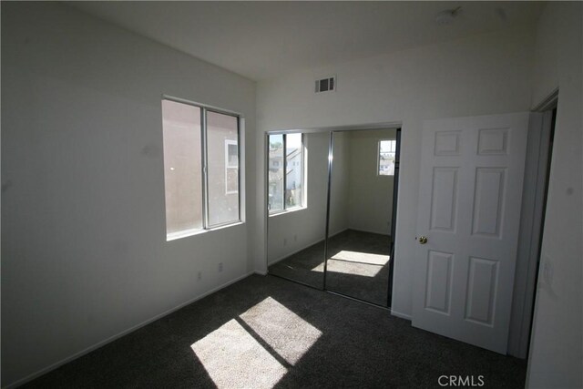 unfurnished bedroom featuring multiple windows and dark colored carpet