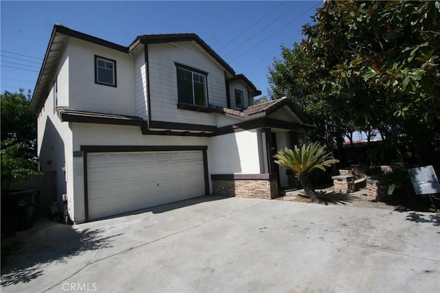 view of front of house with driveway, stone siding, an attached garage, and stucco siding