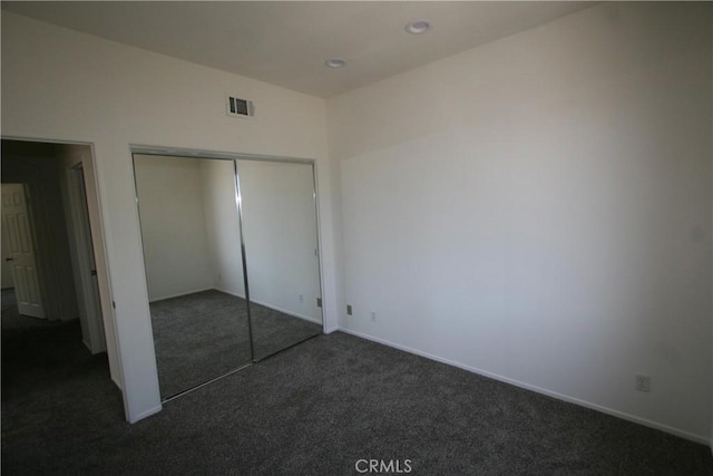 unfurnished bedroom featuring dark colored carpet and a closet